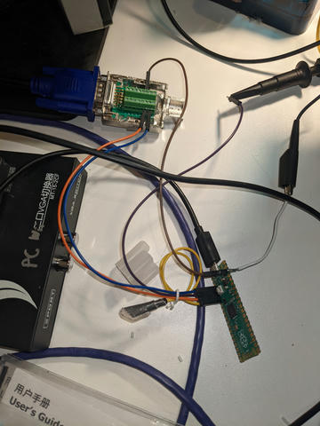 Photo of Pi Pico connected to a VGA splitter between the GBS-C and my monitor, outputting a sync loss signal to an oscilloscope probe.